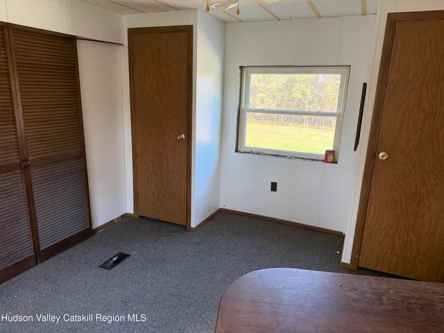 a view of an empty room with window and closet area