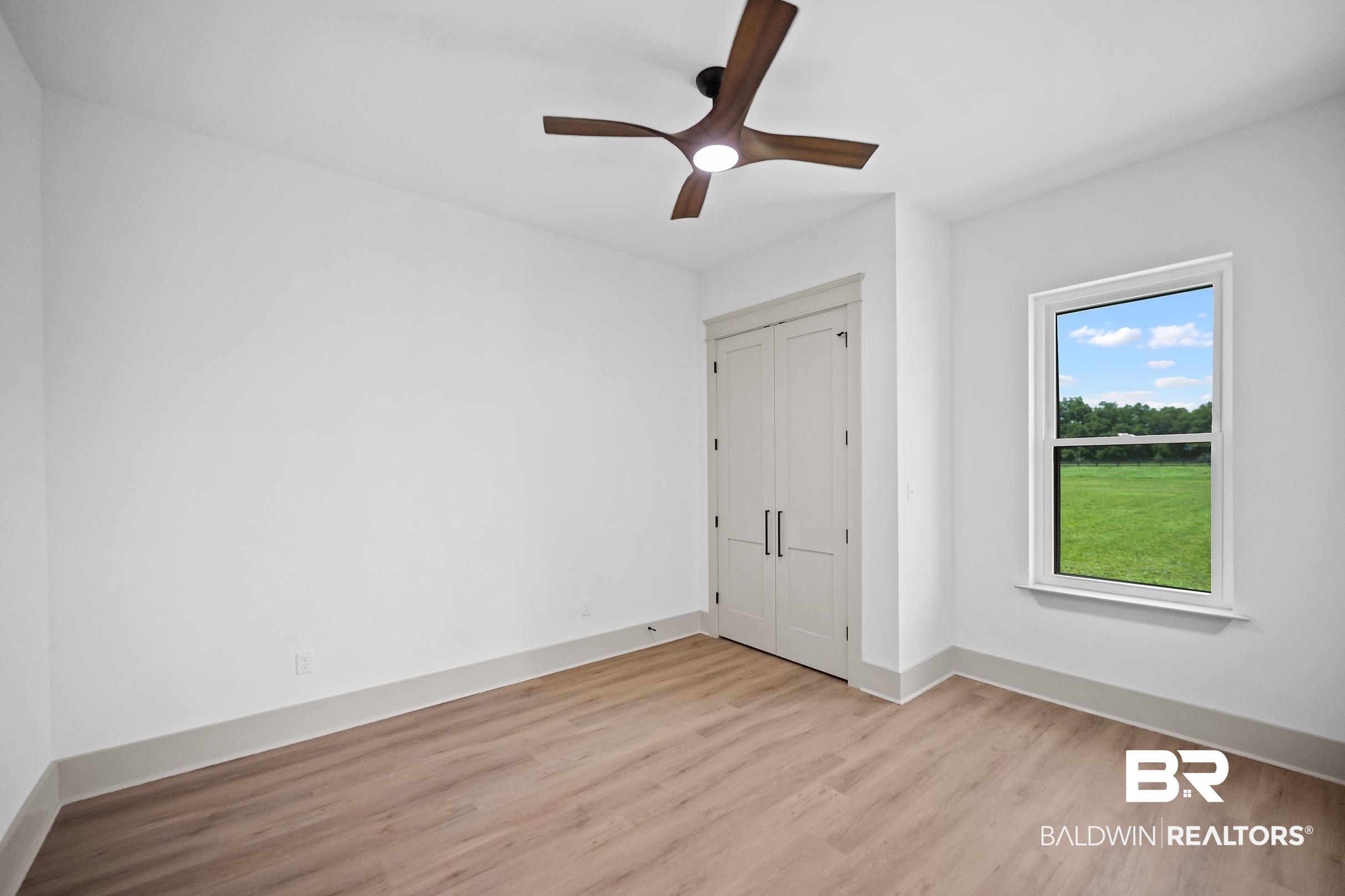 13111 Gopher Court Elberta, AL 36530 - Photo 33 of 41 Interior room featuring wood-finish flooring, a contemporary ceiling fan with integrated lighting, a double-door closet, and a window with a green field backdrop