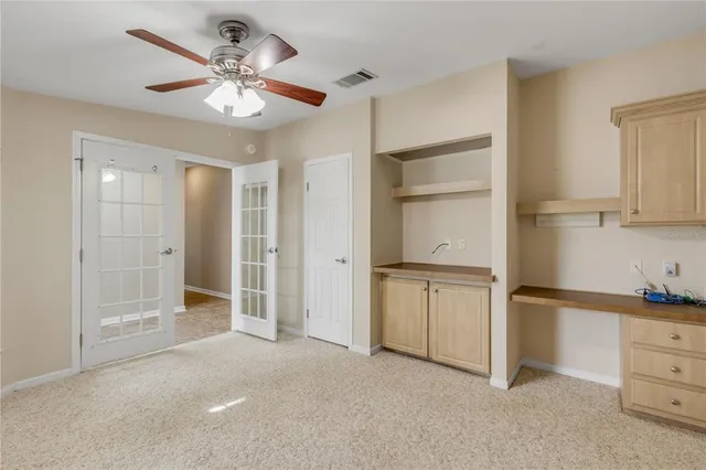 an empty room with wooden floor chandelier fan and windows