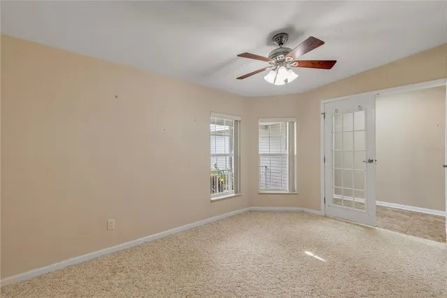 a view of an empty room with wooden floor and a kitchen