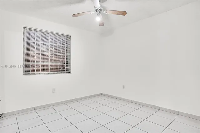 an empty room with a ceiling fan and window