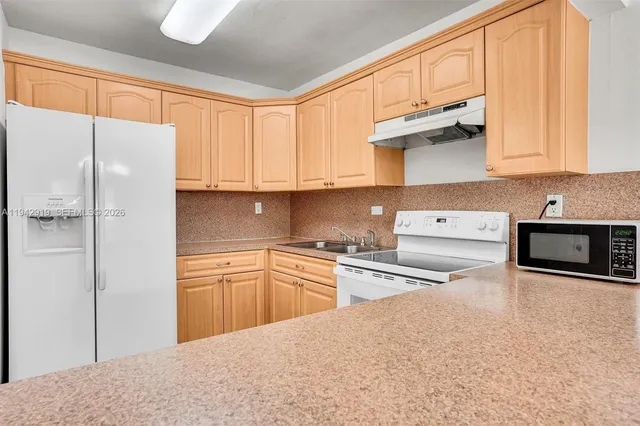 a kitchen with stainless steel appliances granite countertop a refrigerator sink and white cabinets