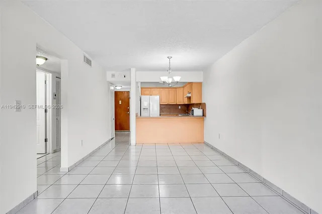a view of a refrigerator in kitchen and an empty room