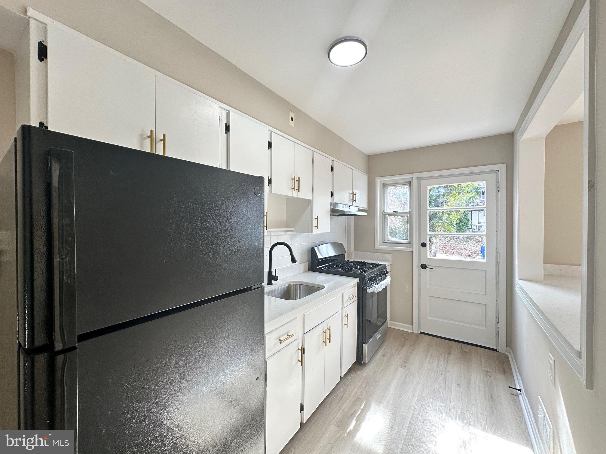 1038 Wedgewood Road Baltimore, MD 21229 - Photo 1 of 12 a kitchen with a sink a stove and cabinets