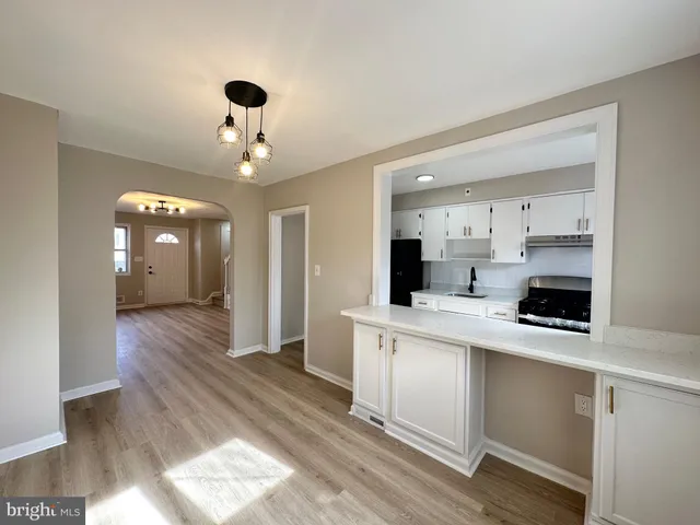 a kitchen view with white cabinets a sink dishwasher and a stove with wooden floor