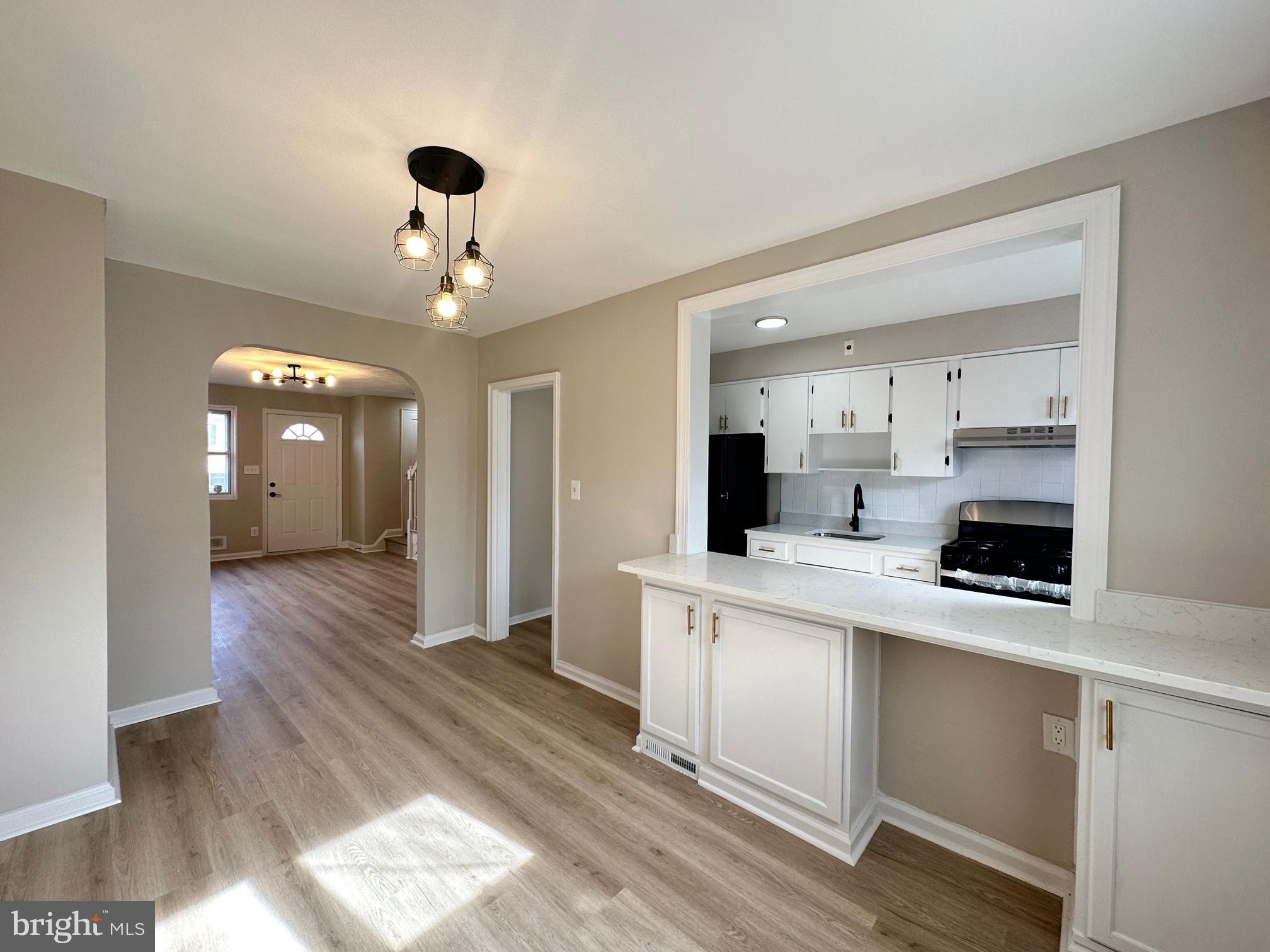 1038 Wedgewood Road Baltimore, MD 21229 - Photo 5 of 12 a kitchen view with white cabinets a sink dishwasher and a stove with wooden floor