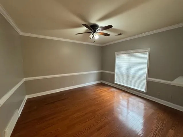 an empty room with wooden floor fan and windows