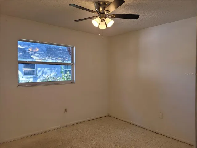 an empty room with a window and a fan