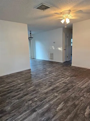 a view of a room with wooden floor and a fan