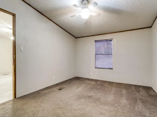 an empty room with a chandelier fan and windows