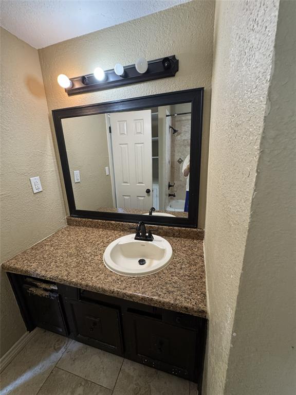 803 Ripley Avenue Ennis, TX 75119 - Photo 26 of 40 Bathroom vanity featuring an oval undermount sink, a dark countertop, and a black framed mirror