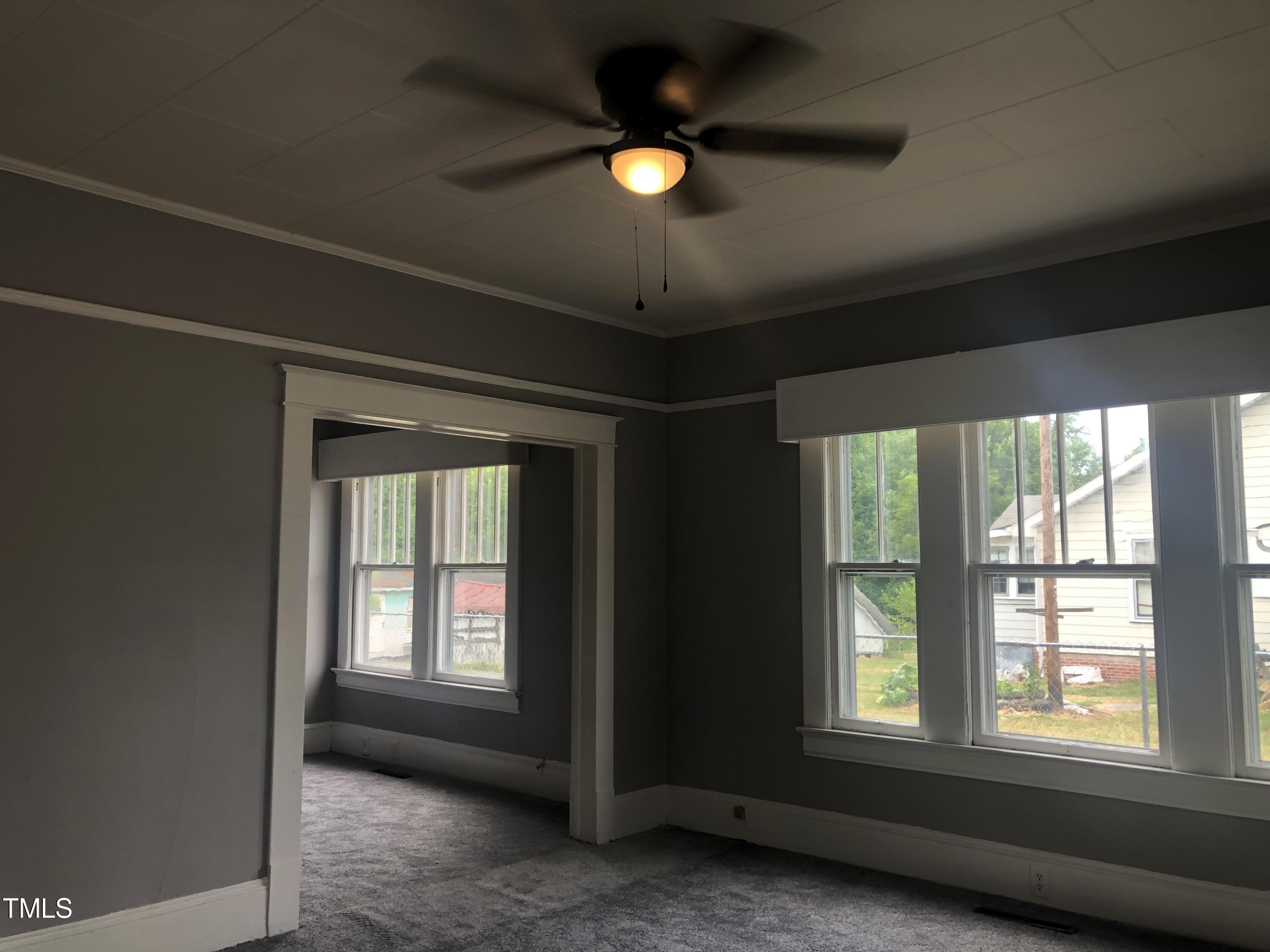 3124 Raleigh Road Henderson, NC 27537 - Photo 5 of 18 an empty room with a window and a ceiling fan