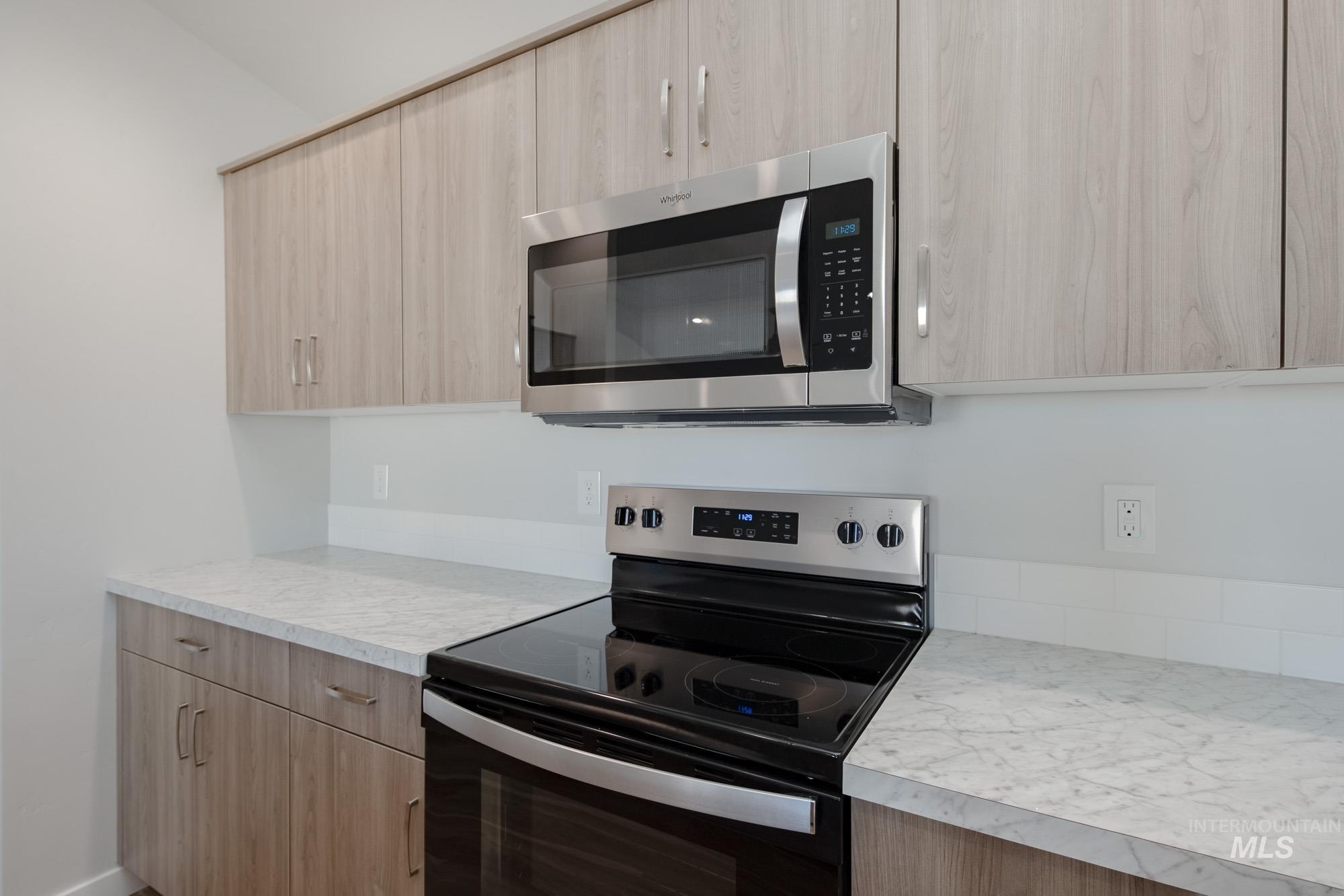 13731 Nisene Street Caldwell, ID 83607 - Photo 11 of 22 Kitchen featuring electric range oven, stainless steel microwave, light countertops, light brown cabinets, and modern cabinets
