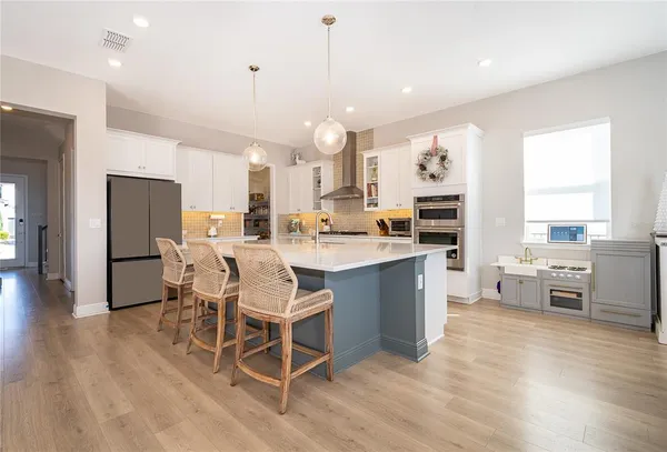 a large white kitchen with a large island oven a stove and white cabinets
