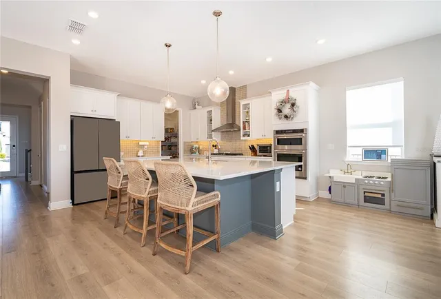 a large white kitchen with a large island oven a stove and white cabinets