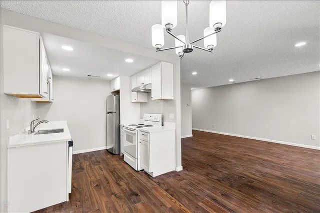 a kitchen with wooden floors and white cabinets