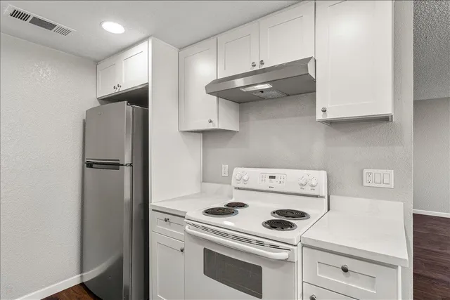 a kitchen with stainless steel appliances white cabinets and a refrigerator