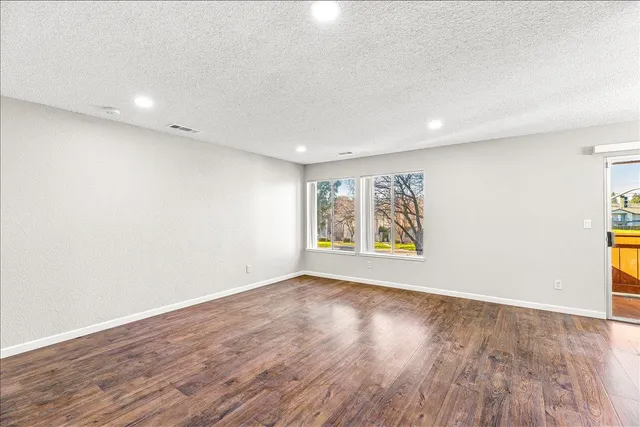 an empty room with wooden floor and window