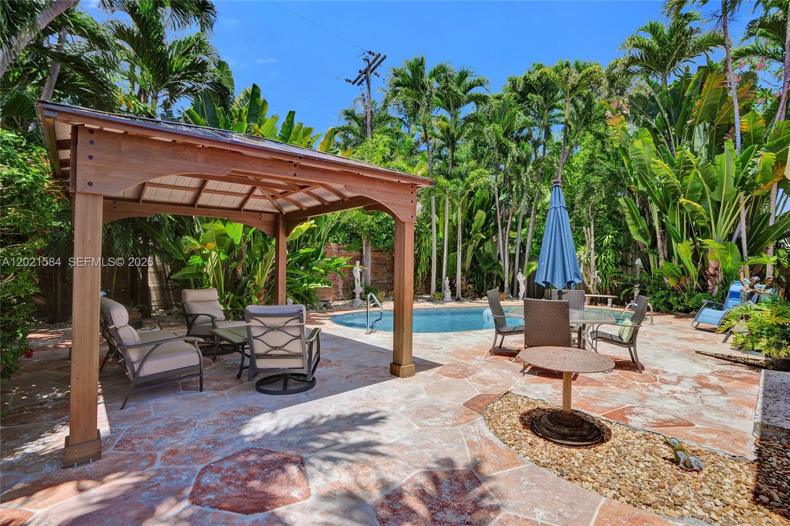 811 Northeast 73rd Street Miami, FL 33138 - Photo 21 of 51 a view of patio with a table and chairs under an umbrella with a small yard