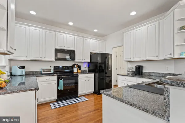 a kitchen with granite countertop a stove sink and refrigerator