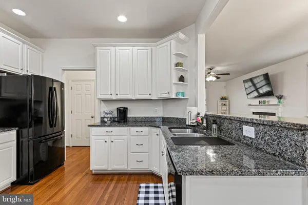 a kitchen with granite countertop a refrigerator stove and sink