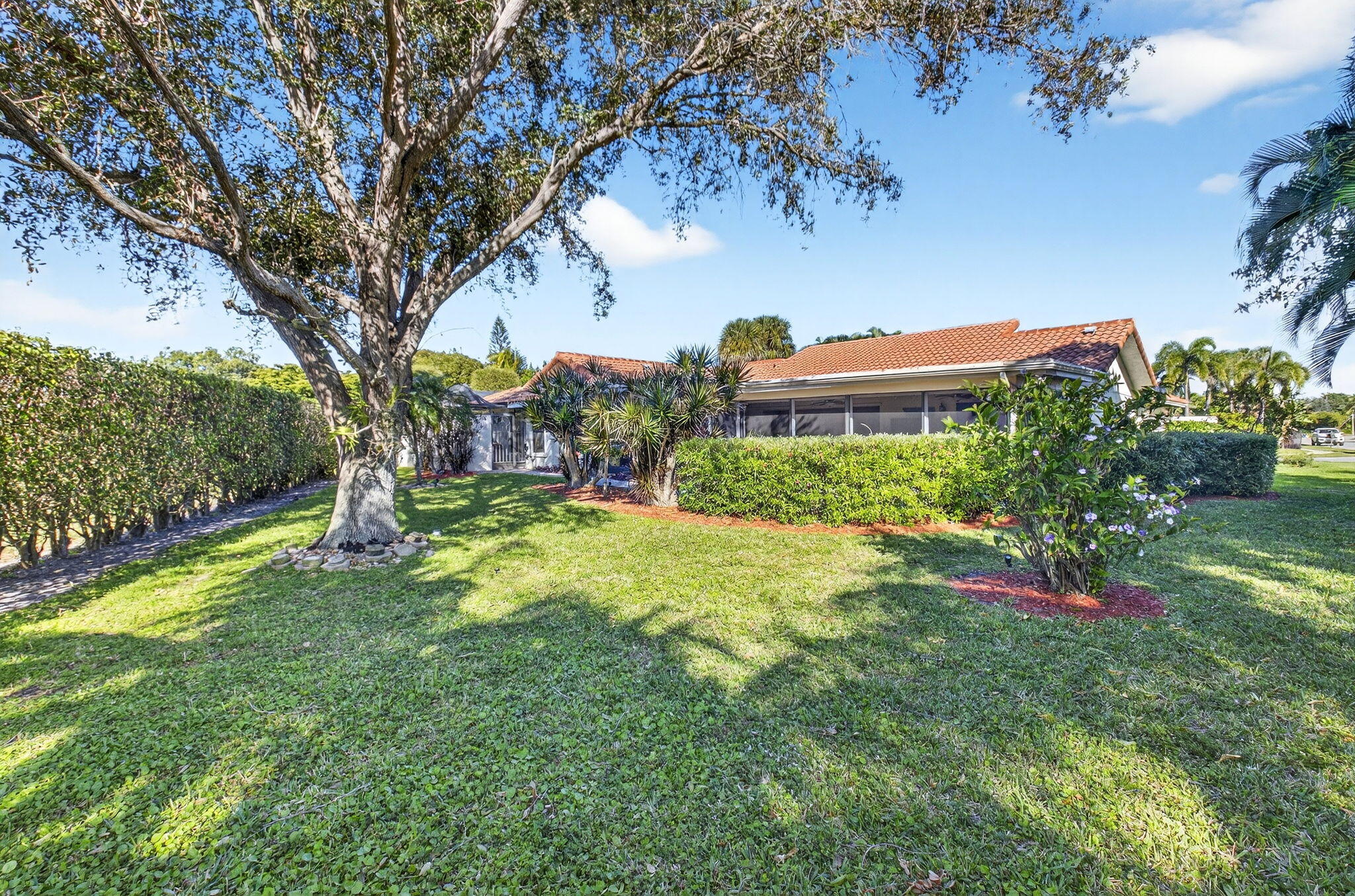 5470 Northwest 3rd Terrace Boca Raton, FL 33487 - Photo 56 of 72 a backyard of a house with table and chairs plants and large trees