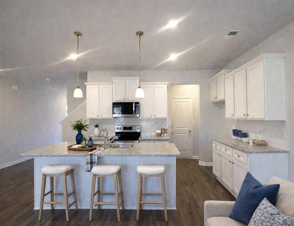 6343 Towhee Way Morrow, GA 30260 - Photo 4 of 36 a kitchen with stainless steel appliances kitchen island granite countertop a stove a sink a microwave a refrigerator and white cabinets with wooden floor