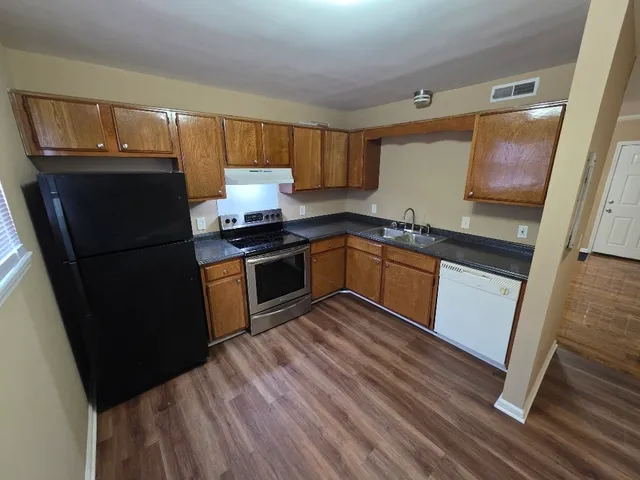 a kitchen with granite countertop stainless steel appliances a stove a sink and a refrigerator