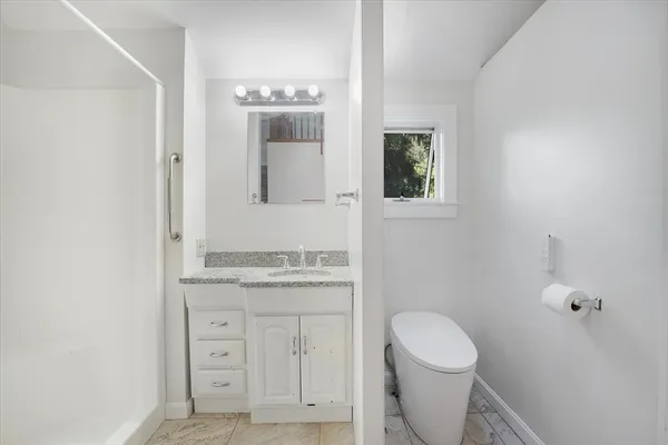 a bathroom with a granite countertop toilet sink and mirror