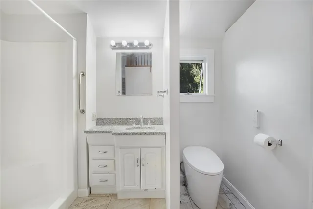 a bathroom with a granite countertop toilet sink and mirror