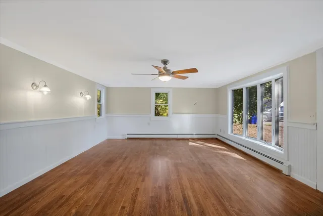 a view of an empty room with window and wooden floor