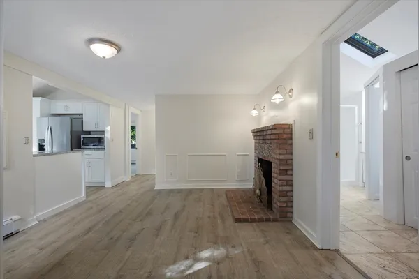 a view of a hallway with wooden floor and a kitchen