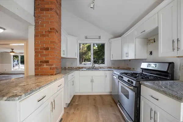 a kitchen with granite countertop stainless steel appliances a stove sink and cabinets
