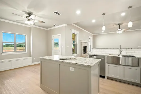a kitchen with kitchen island granite countertop a sink and white cabinets