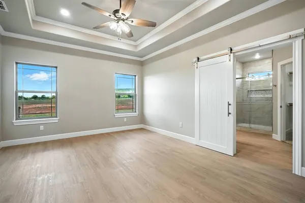a view of an empty room with glass door and a chandelier fan