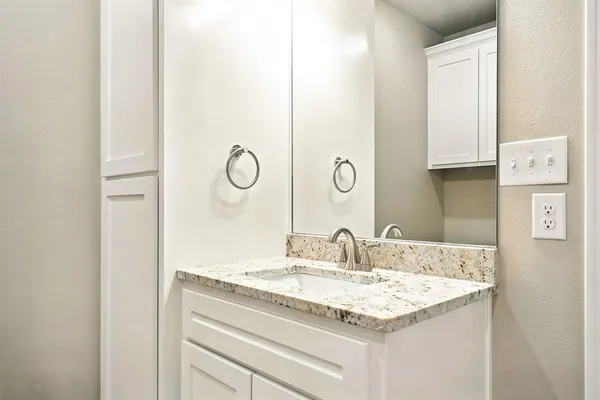 a bathroom with a granite countertop sink and a mirror