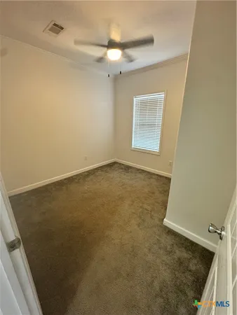 an empty room with a ceiling fan and a rug