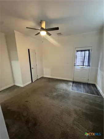 an empty room with windows and fan