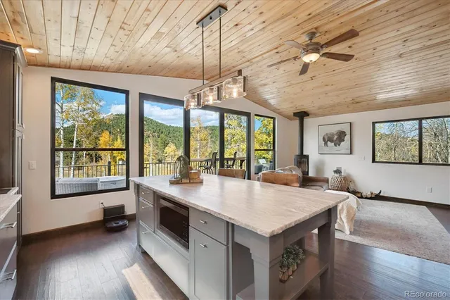 a open kitchen with a stove a refrigerator a sink a dining table and chairs with wooden floor