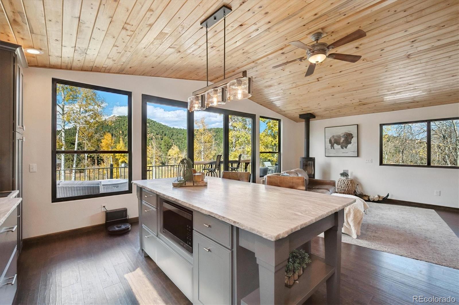 a open kitchen with a stove a refrigerator a sink a dining table and chairs with wooden floor