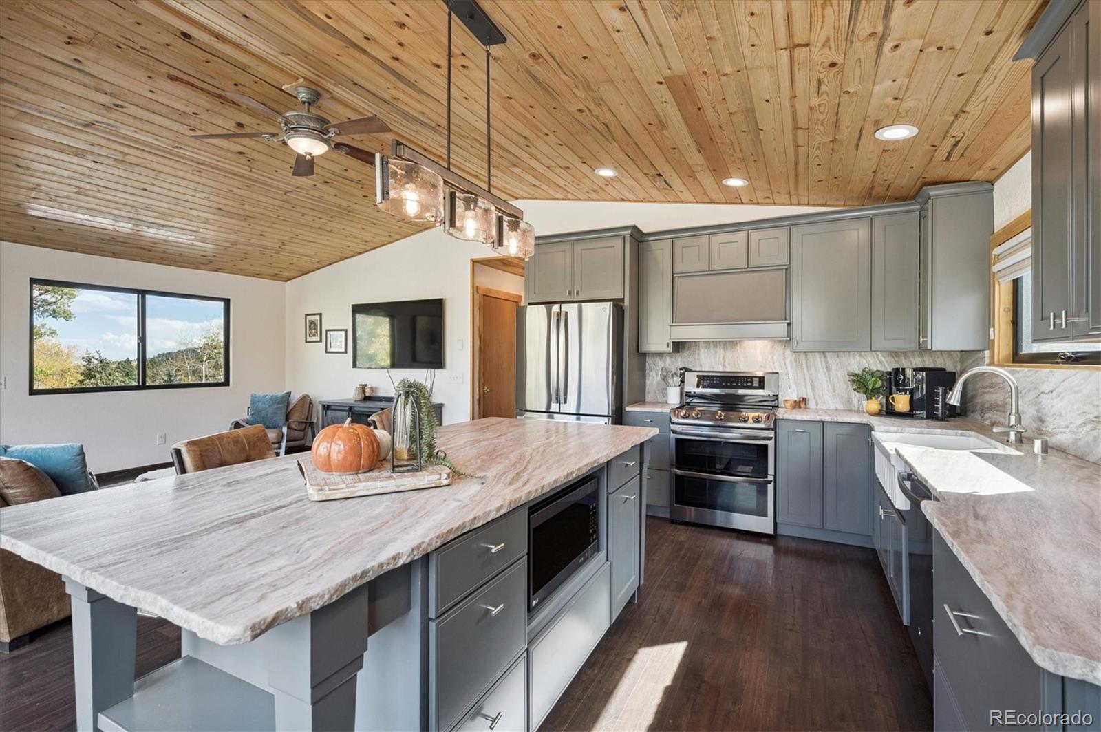 12369 Quartz Spur Conifer, CO 80433 - Photo 11 of 36 a kitchen with stainless steel appliances granite countertop wooden cabinets a stove top oven a sink dishwasher a dining table and chairs with wooden floor
