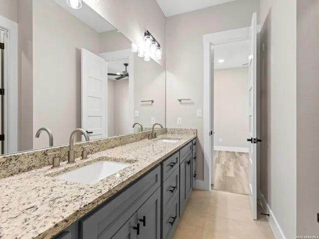 a bathroom with a granite countertop double vanity sink and a mirror