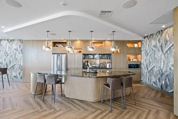 a kitchen with stainless steel appliances kitchen island granite countertop a table chairs and a refrigerator