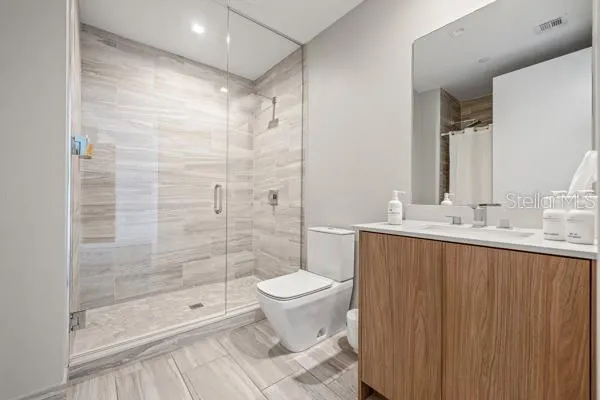 a bathroom with a shower sink mirror and toilet