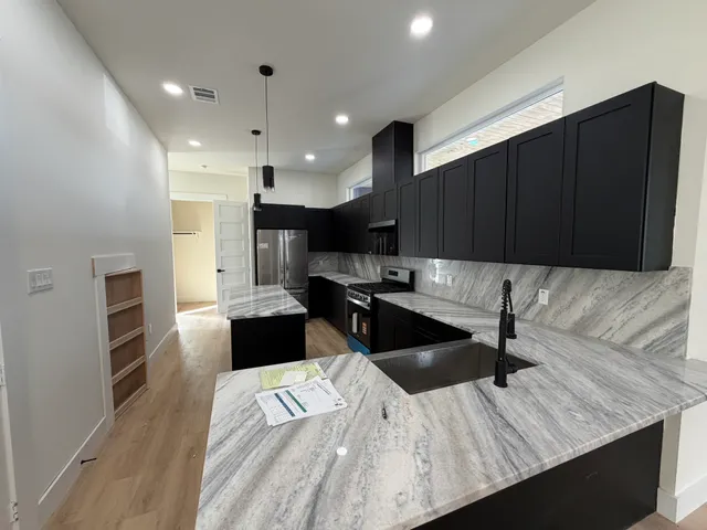 a large kitchen with a counter space a sink and stainless steel appliances