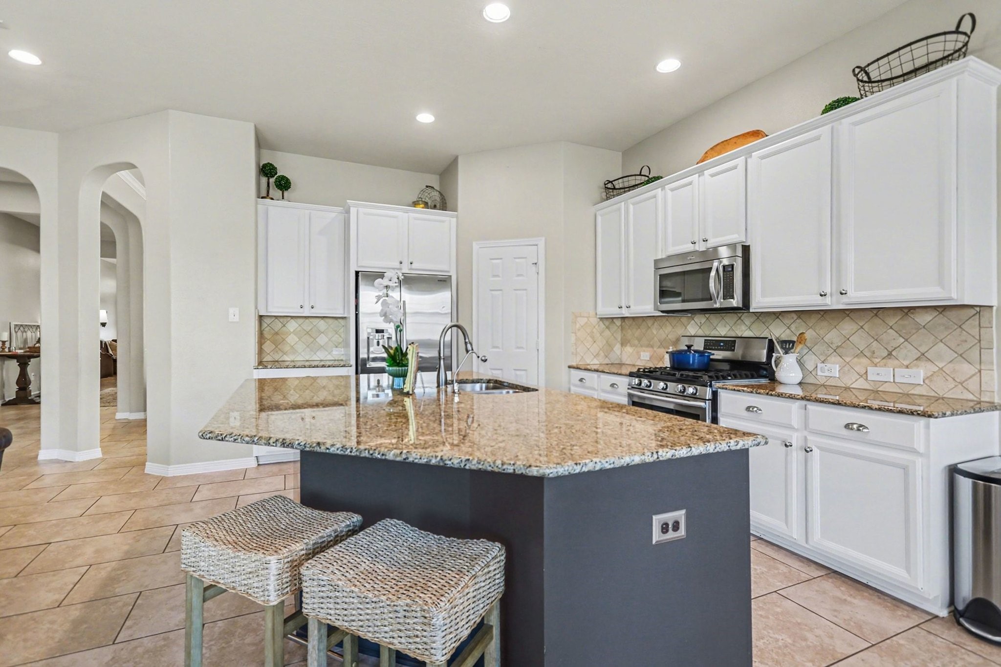 27006 Cliff Pointe Lane Katy, TX 77494 - Photo 11 of 34 Bright, open kitchen designed for gathering, featuring crisp white cabinetry, granite countertops, tile backsplash, and a generous island with seating—perfect for everyday living and entertaining.