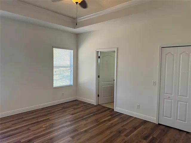 an empty room with wooden floor cabinet and windows