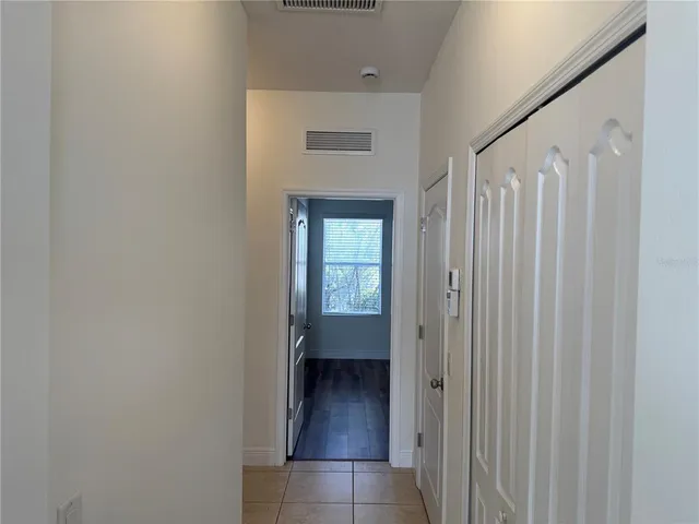 a view of a hallway with wooden floor and a bathroom