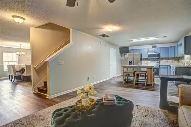 a living room with furniture and kitchen view with wooden floor