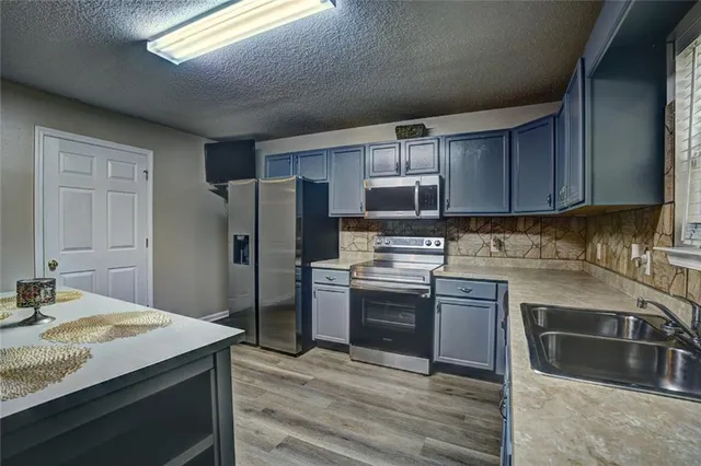 a kitchen with kitchen island granite countertop a sink stove and refrigerator